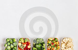 Border of frozen vegetables in plastic containers on a white background. Frozen food. Copy space, view from above