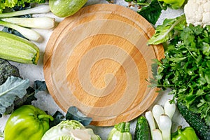 Border of green raw vegetables around empty cutting board. Place for your product or text.