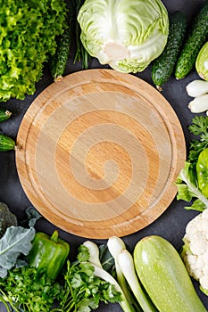 Border of green raw vegetables around empty cutting board. Place for your product or text.