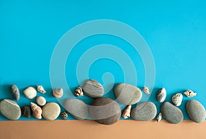 The border is made of grey sea pebbles and shells on a light blue and beige background.