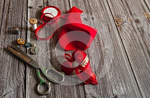 The border is made of scraps of red fabric, ribbons, scissors, thread and sewing accessories on a wooden background.