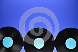 Border of old black vinyl records on blue background