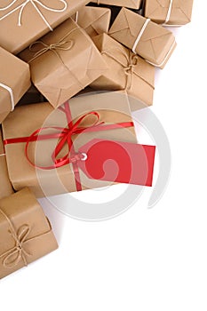 Border of small pile of brown paper parcels, red gift tag, isolated