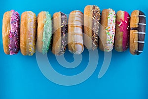 Bordure of different kinds of donuts on blue background with copy space.