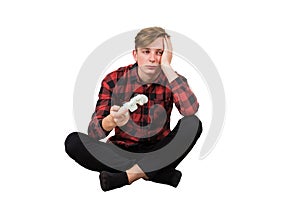 Bored adolescent boy seated on the floor playing video games isolated over white background. Sleepy boy holding joystick console,