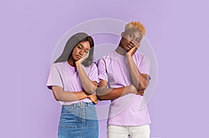 Bored African American couple with dull facial expressions on color background