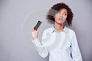 Bored afro american woman holding smartphone