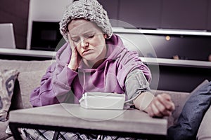 Bored bold woman measuring her blood pressure