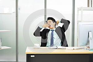 Bored Businessman sitting at workplace near computer feeling sleepiness exhaustion and tiredness after long hard working day.