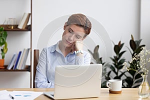 Bored businesswoman sleeping on hand sitting at office desk