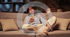 Bored Caucasian Woman Yawning with Phone on Sofa