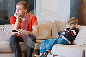 Bored child and father is watching TV