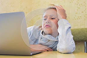 Bored child girl looks at computer. distance learning uninteresting.