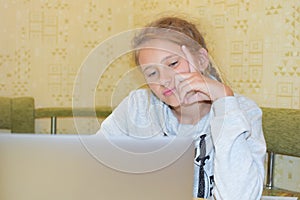 Bored child girl looks at computer. distance learning uninteresting.