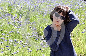 Bored child scratching head having concerns over blooming floral field