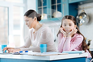 Bored child standing near her mom working