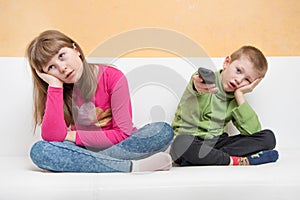 Bored children sitting on the couch watch TV during the Coronavirus quarantine