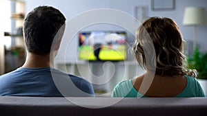 Bored couple watching football match on tv, conflict, passive pastime together
