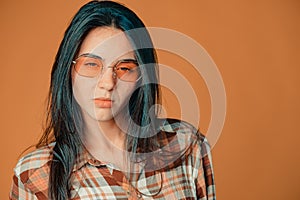 Bored cute young brunette girl showing mistrust on orange background