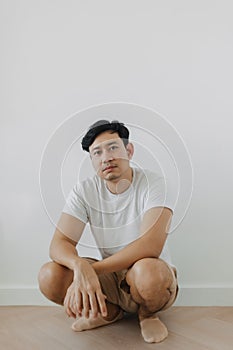 Bored face Asian man squatting on the floor with white background