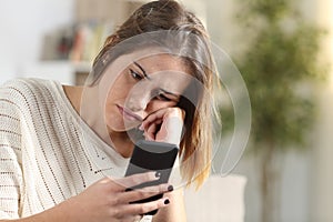 Bored girl holding smart phone at home