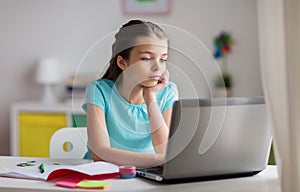 Bored girl with laptop and notebook at home