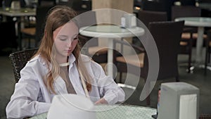 Bored girl removing hat from head while sitting at restaurant