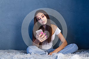 Bored girl sitting on the bed with phone. Insomnia concept.