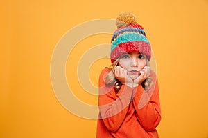 Bored girl in sweater and hat reclines on her arms