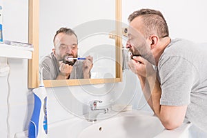 Bored guy brushing his teeth in bathroom