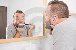 Bored guy brushing his teeth in bathroom