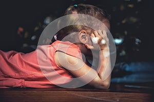 Bored lonely child girl lying on windowsill in home isolation opposite window