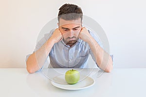 Bored man eating only one apple for diet