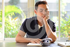 Bored man reading book with hand on chin