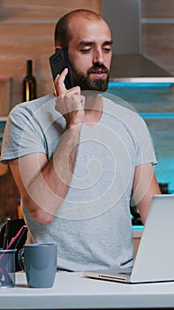 Bored man in t-shirt yawning while talking on smartphone