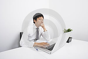 Bored mid adult businessman using laptop at desk in office