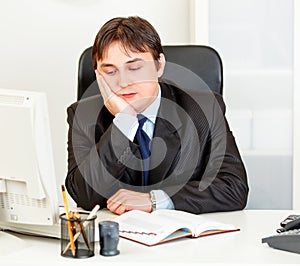 Bored modern businessman sitting at desk in office