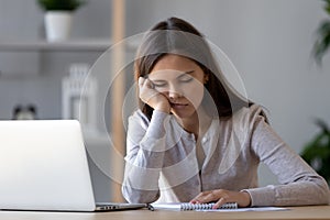 Bored funny woman resting on hand sleeping at workplace photo