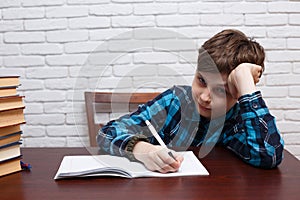 Bored schoolboy ponders over the task solution. Elementary schoo