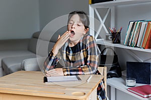 Bored secondary school girl yawning. Young learner tired of studying, reading books and classes