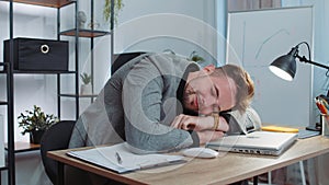 Bored sleepy business man worker working on laptop computer, yawning, falling asleep at office