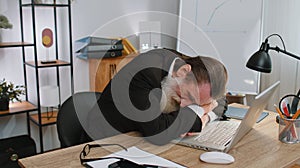 Bored sleepy business man worker working on laptop computer, yawning, falling asleep at office