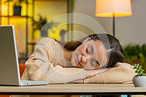 Bored sleepy business woman worker works on laptop leaning on hands falling asleep at home table