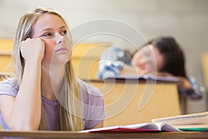 Bored student listening while classmate sleeping