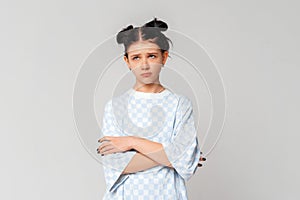 Bored teen girl looking aside with sad, gloomy and unamused expression, standing upset and moody in trendy t shirt over light grey