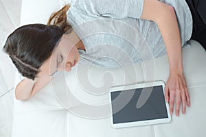 Bored teenage girl lays in bed with tablet computer