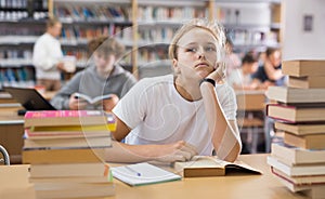 Bored teenage girl trying to prepare for exam in library