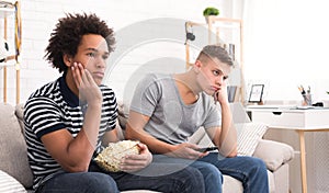 Bored teens watching dull movie with popcorn