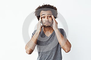 Bored tired african man touching face with hands over white background.
