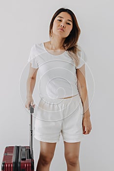 Bored and tired face woman in her private loungewear and baggage isolated on white.